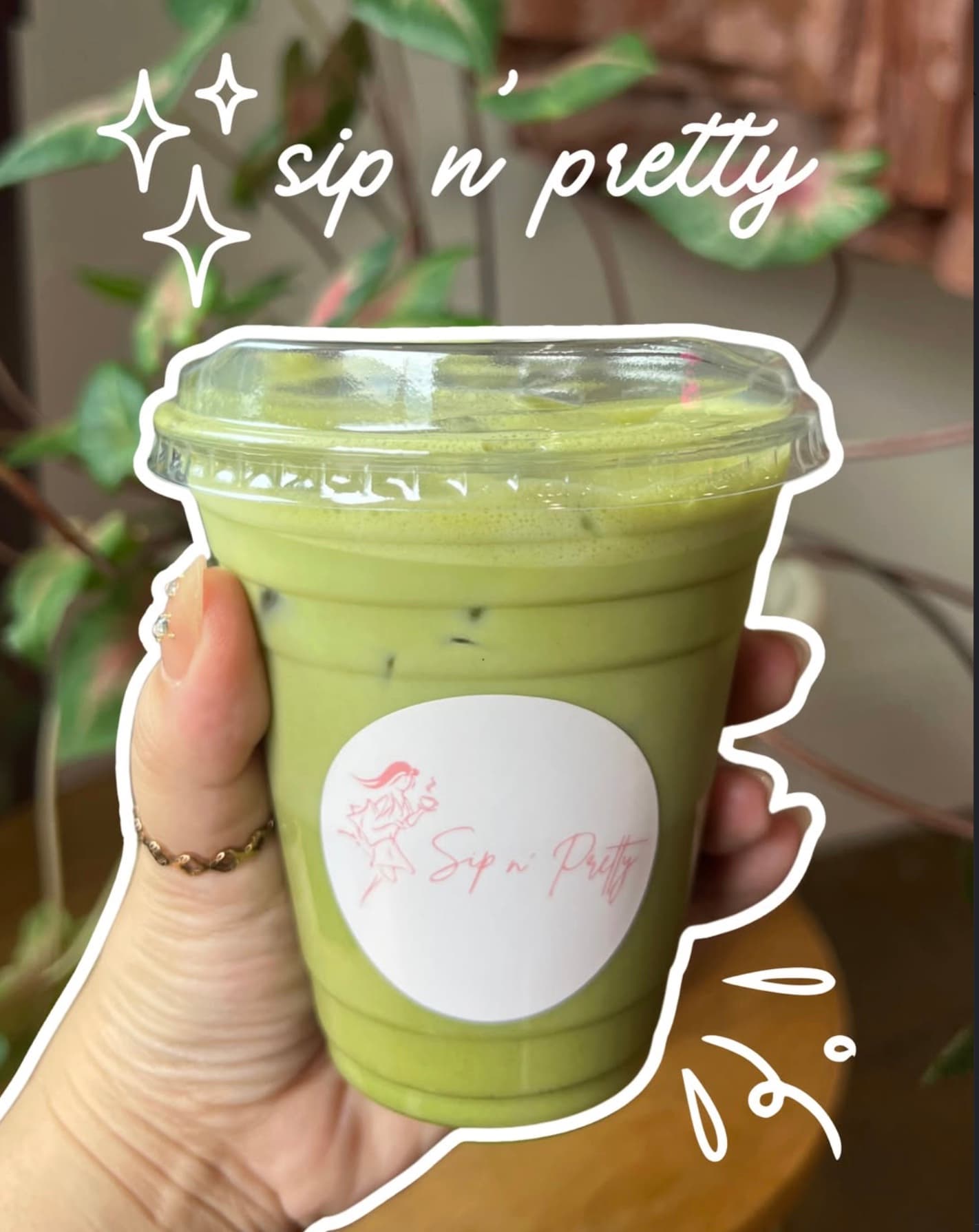 A Sip N' Pretty matcha latte, vibrant green, in a hand, with sparkle illustrations and 'sip n' pretty' caption.